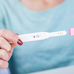 Woman’s hand’s holding at-home pregnancy test strip 