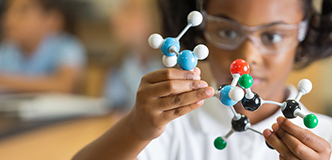 Elementary science student using plastic atom model educational toy.