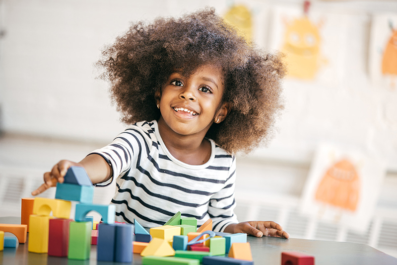 Preschool age child playing with blocks at a desk.