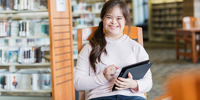 Adolescent with Down syndrome holding computer tablet.