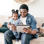 Adult and toddler looking at a tablet screen.