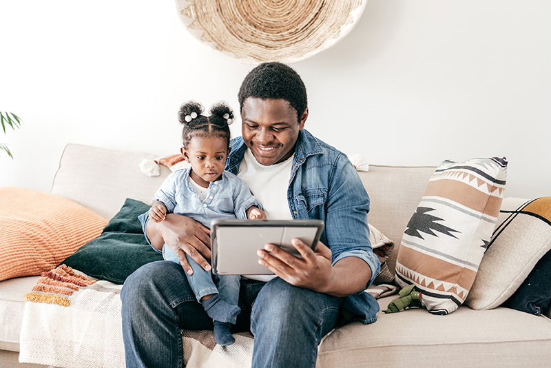 Adult and toddler looking at a tablet screen.