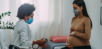 Pregnant woman in a healthcare provider’s office talking with the doctor.