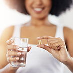 Pregnant woman holding clear medicine/nutrition capsule.