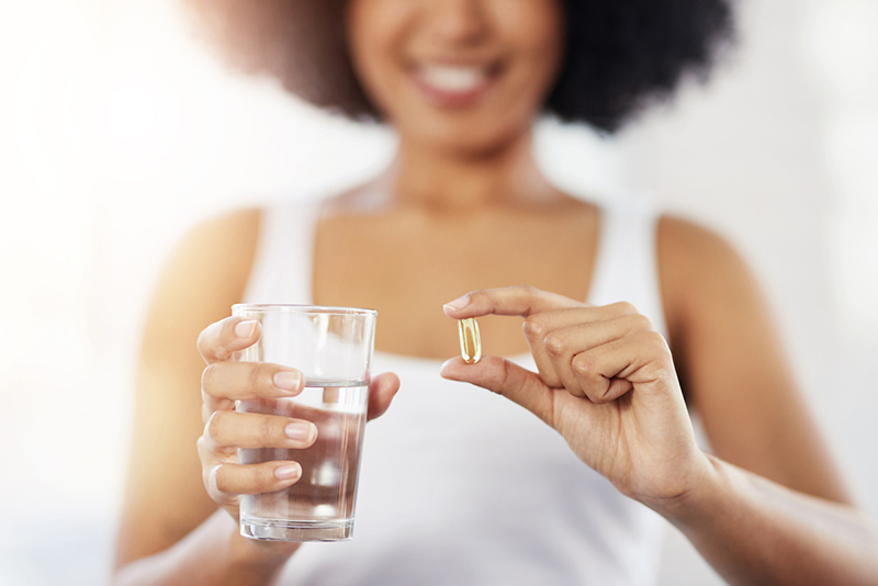 Pregnant woman holding clear medicine/nutrition capsule.