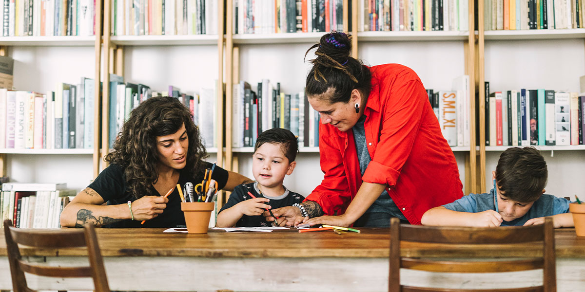 Women at long writing table with two male children