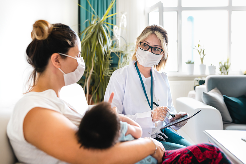 Woman holding infant and talking with healthcare provider.