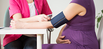 A technician takes a pregnant person’s blood pressure.