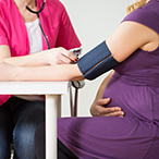 A technician takes a pregnant person’s blood pressure.