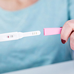 Woman holding a pregnancy test in her hands.