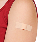 Woman wearing a red shirt with a band-aid on her upper arm.