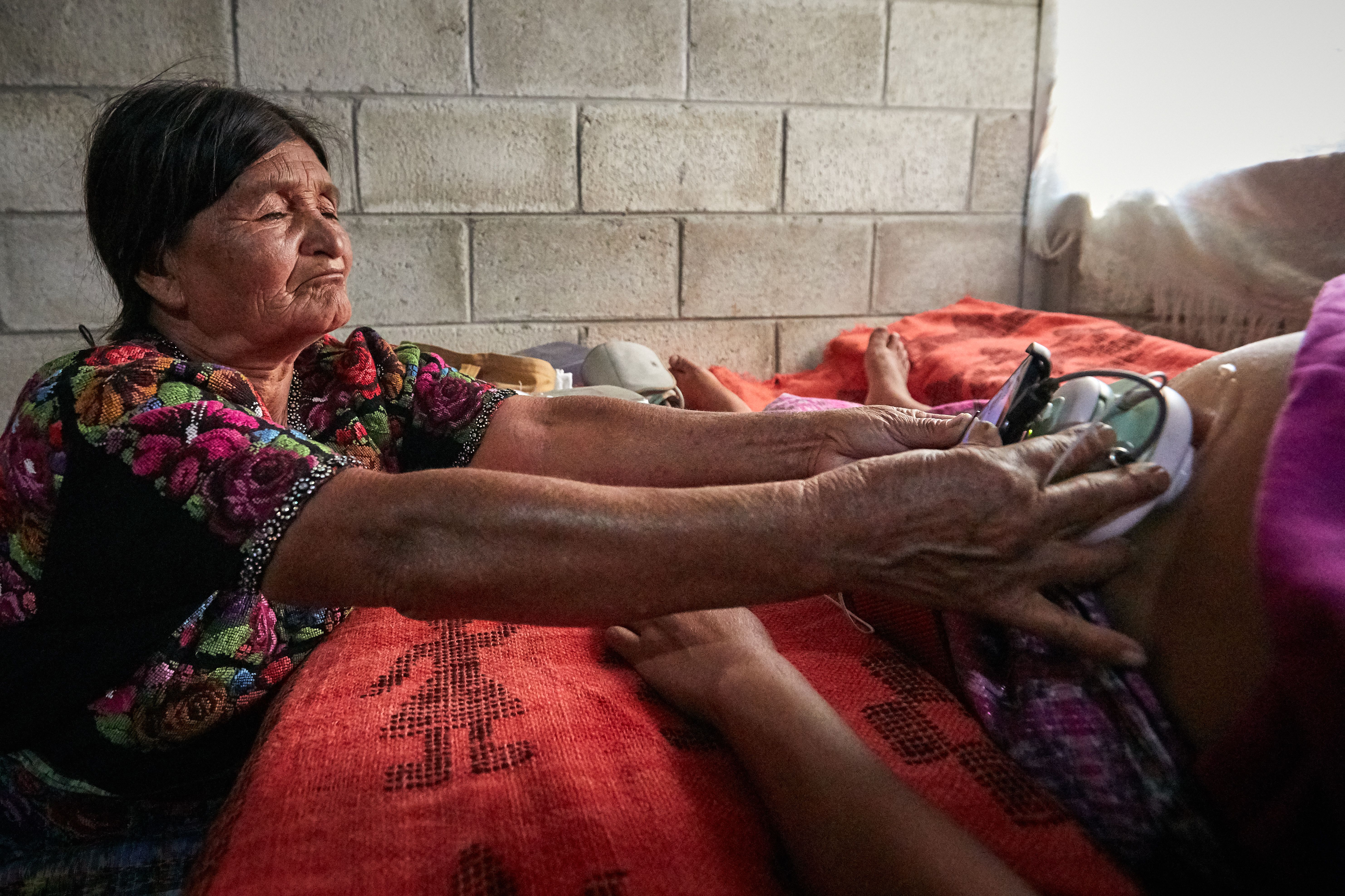 A woman holds a mobile health tool across a pregnant woman’s belly.