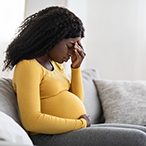 Pregnant woman with her hand over her eyes.