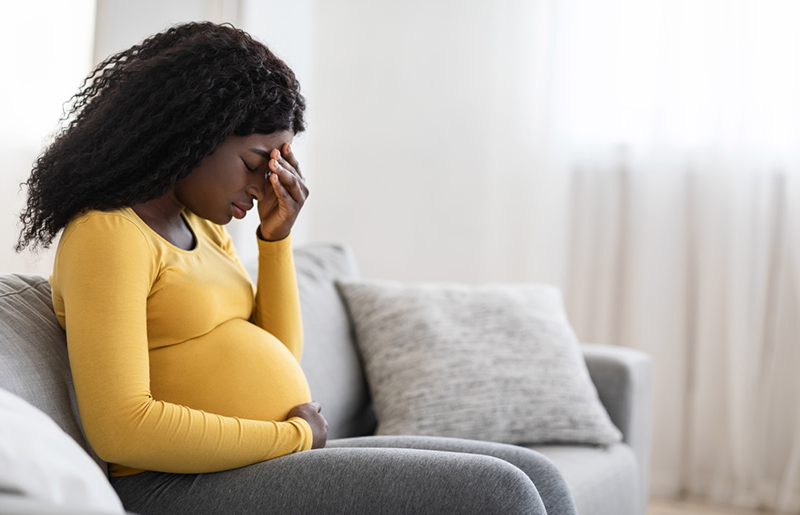 Pregnant woman with her hand over her eyes.