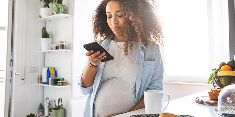 Pregnant person holding a mobile device.