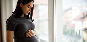 Pregnant person facing a window.
