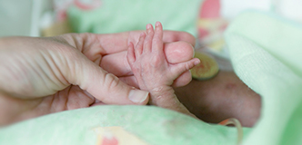 Tiny infant hand holding adult finger.