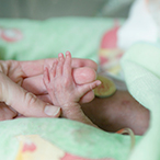 Tiny infant hand holding adult finger.