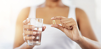 Pregnant woman holding a clear medicine/nutrition capsule.