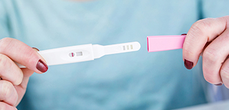 Hands holding a pregnancy test stick.