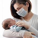 Masked parent holding infant.