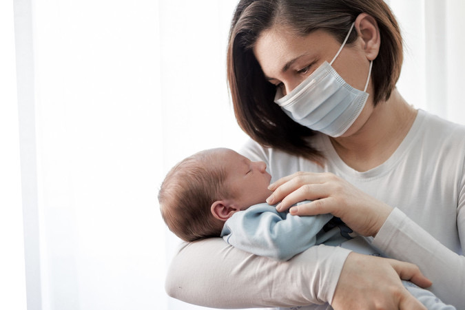 Masked parent holding infant.