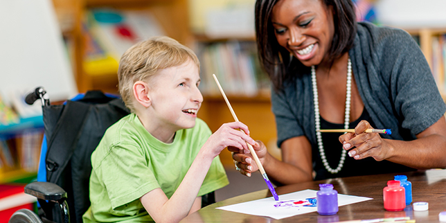 African American teacher works on painting with a blind student.