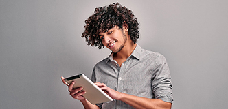 A smiling young man uses a tablet computer.