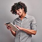 A smiling young man uses a tablet computer.