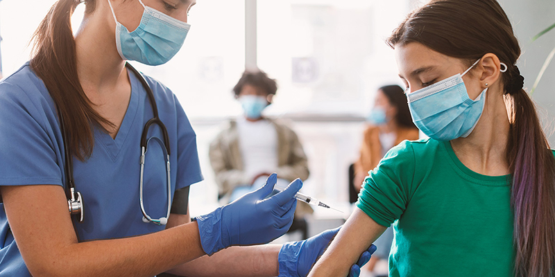 Medical professional giving an injection in a child’s arm.