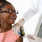 A healthcare provider uses the Buzzy device on a girl’s arm.