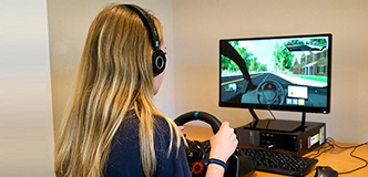 Teen at the steering wheel in front of the virtual driving assessment.