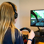 Teen at the steering wheel in front of the virtual driving assessment.