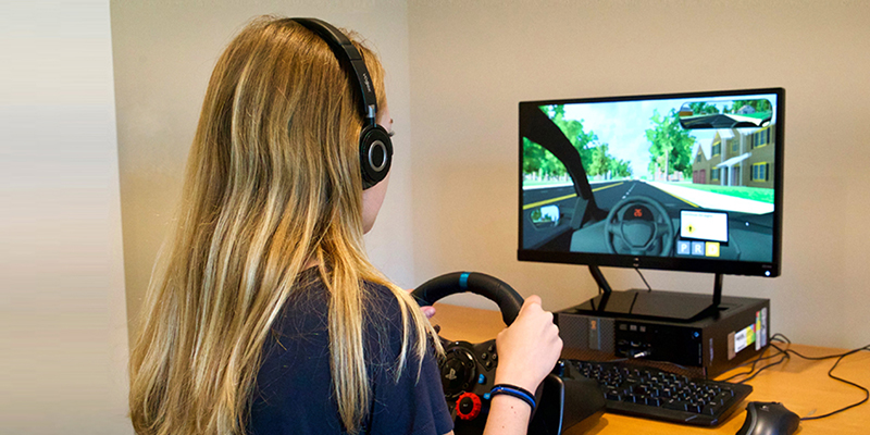 Teen at the steering wheel in front of the virtual driving assessment.