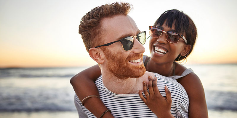 A man and woman are laughing along the beach.