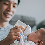 A man bottle-feeding a baby.