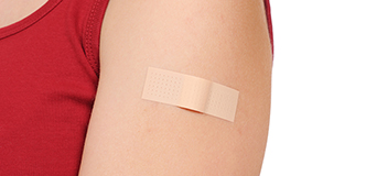 Shoulder with bandaid, presumably covering injection site.