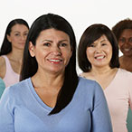 Group of women of different ethnicities and sizes standing together and smiling at the camera.