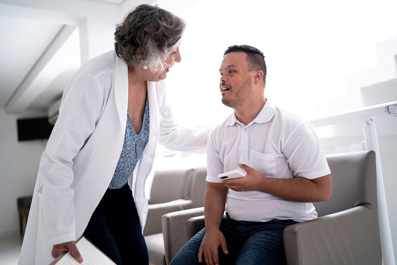Medical professional talking to a person with Down syndrome.