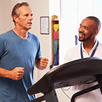 Patient on treadmill while medical professional looks on.