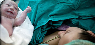 A newborn is presented to their mother immediately after delivery.