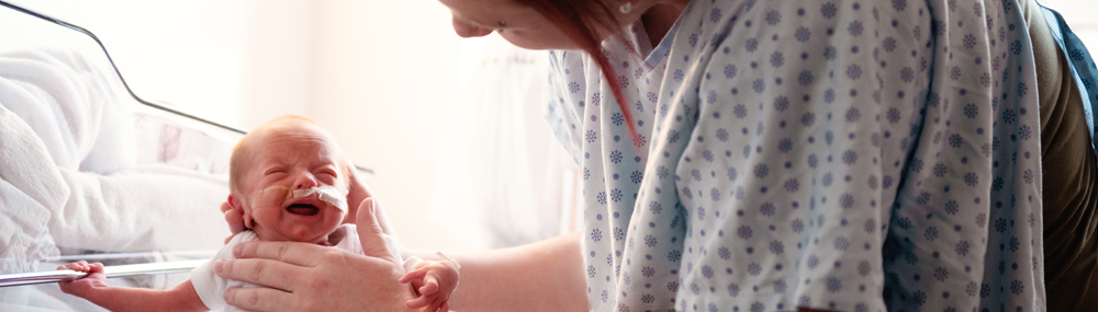 A parent holds and looks down at a newborn baby.