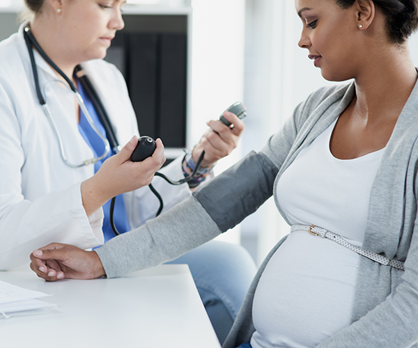 A health care provider checks a pregnant patient’s blood pressure.