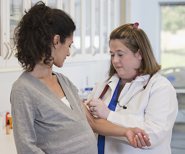 A healthcare provider takes blood from the inner arm of a pregnant woman.