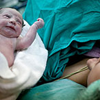 A newly delivered baby is handed to its mother.