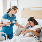 Practitioner at bedside of new parent with hand over eyes, holding newborn.