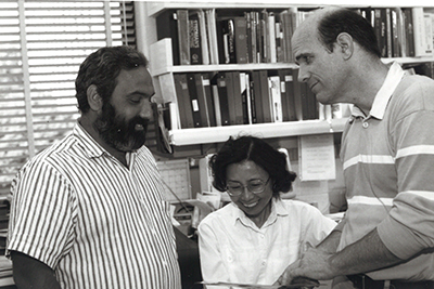 Black and white, undated photograph of the researchers discussing data in a lab.