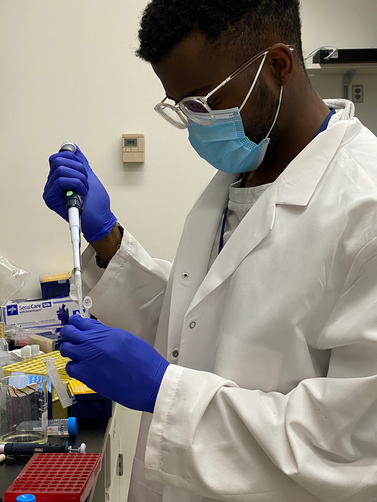 Jacob pipetting while wearing personal protective equipment.