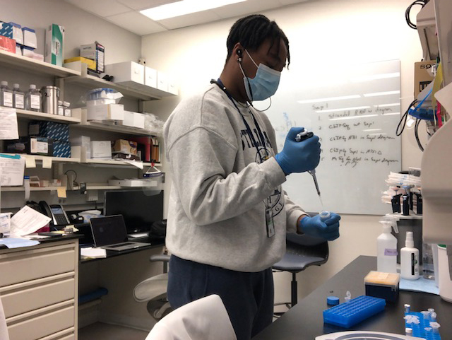 Kyla pipetting while wearing personal protective equipment.
