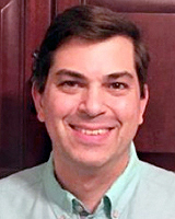 A man smiles against a wooden door.